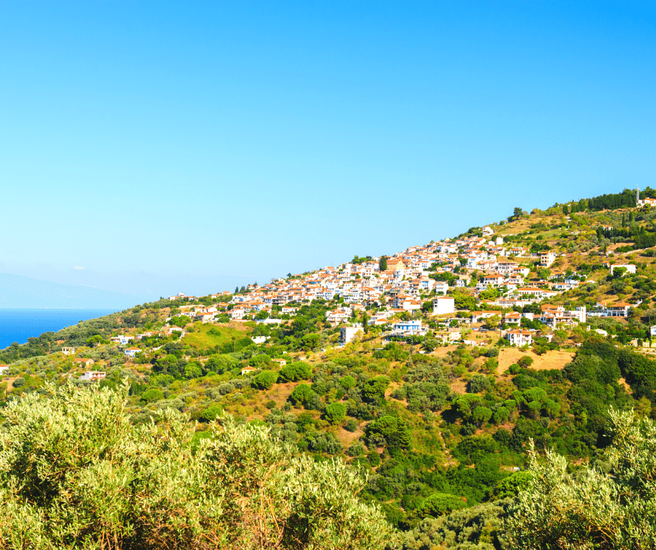 a village on a hillside with white buildings and orange tiled roofs - glossa skopelos